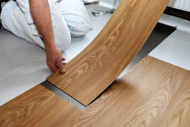 Handwerker verlegt Vinylboden in Holzoptik auf weißem Untergrund